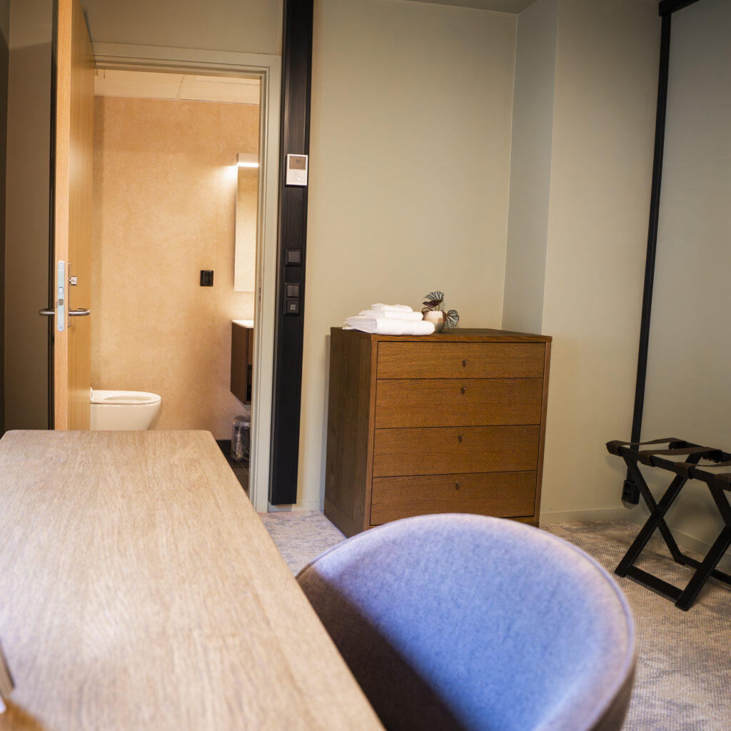 Enkeltrom på Haraldsplass Gjestehus med skrivebord, kommode og dør inn til badet.