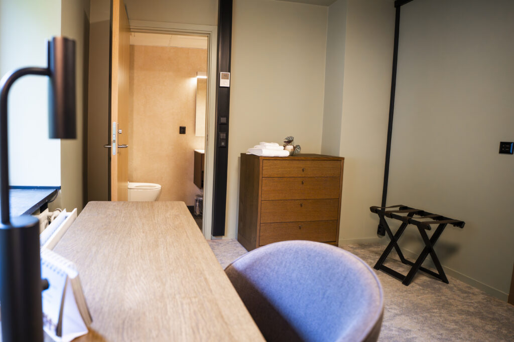 Enkeltrom på Haraldsplass Gjestehus med skrivebord, kommode og dør inn til badet.
